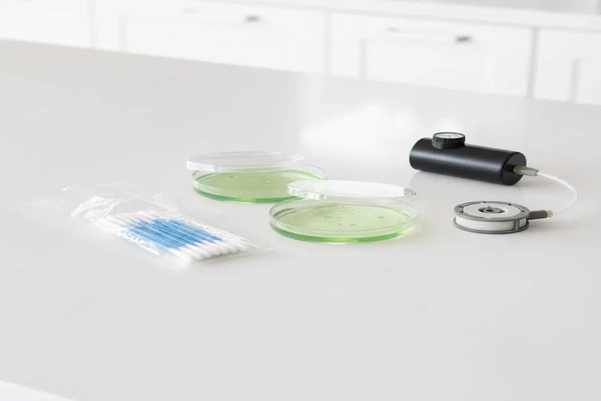 DIY mold test kit with petri dishes, swabs, and air sampling cassettes on a clean surface