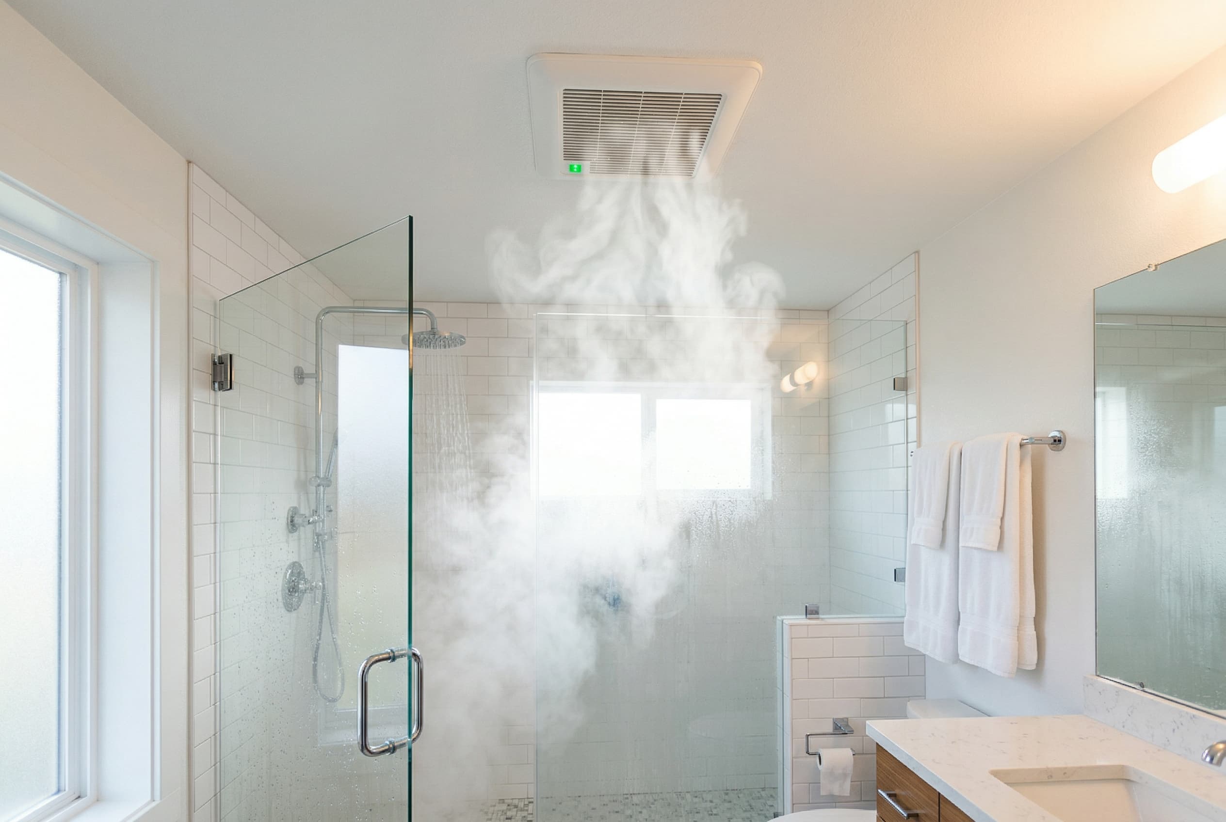 Bathroom exhaust fan running with visible steam being pulled upward near the ceiling in a modern white-tiled bathroom